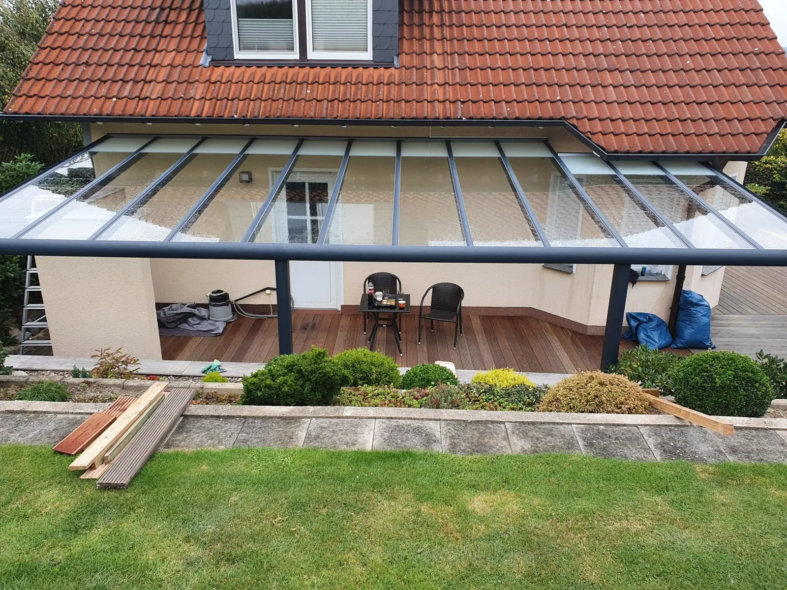 Terrassenüberdachung mit Glasdach über einer Holzterrasse
